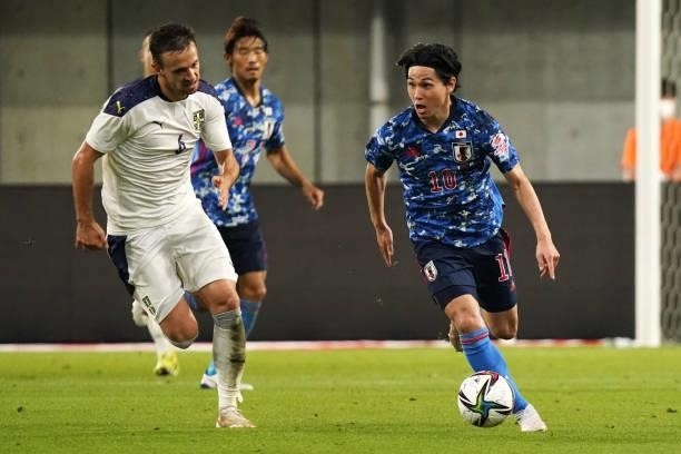 Takumi Minamino of Japan takes on Nemanja Maksimovic of Serbia during the international friendly match between Japan and Serbia at Noevir Stadium...