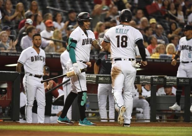 Carson Kelly of the Arizona Diamondbacks celebrates with Ketel Marte after scoring on a fielders choice hit by Christian Walker against the Los...