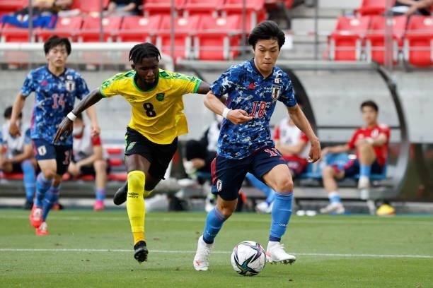 Ryotaro Meshino of Japan U-24 controls the ball under pressure of Oniel Fisher of Jamaica during the international friendly match between Japan U-24...