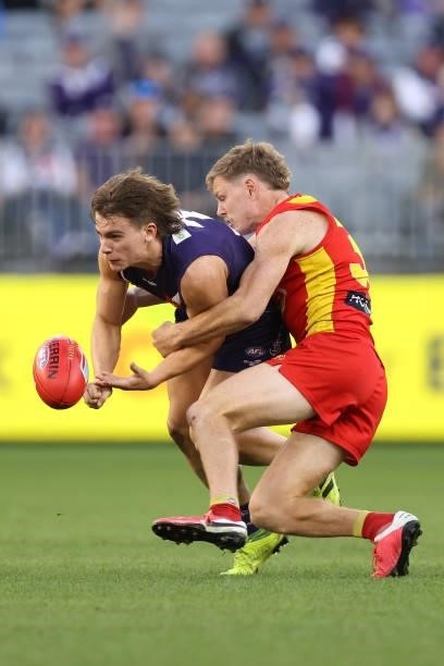 Caleb Serong of the Dockers gets his handball away under pressure by Nick Holman of the Suns during the round 13 AFL match between the Fremantle...