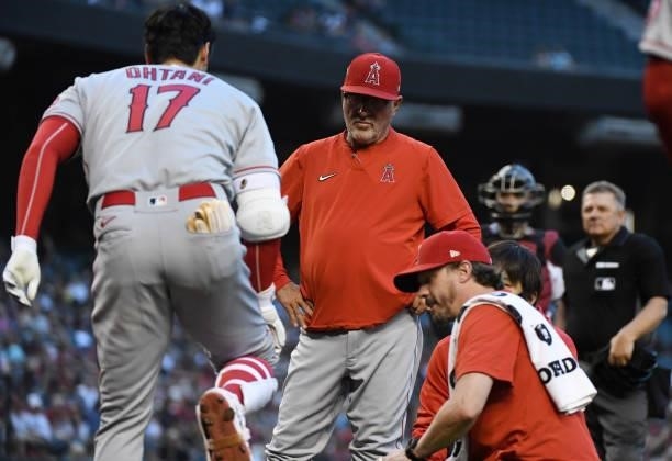 Manager Joe Maddon of the Los Angeles Angels checks on Shohei Ohtani after he hit a foul ball off of his knee during the third inning against the...