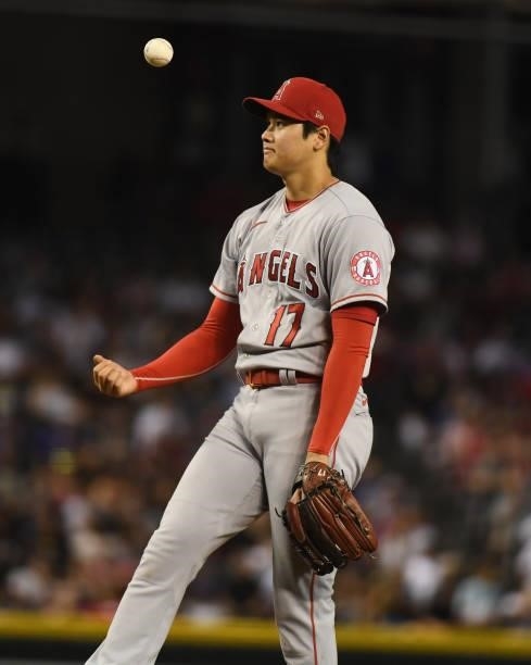 Shohei Ohtani of the Los Angeles Angels tosses the ball up in the air after giving up a run on a balk during the fifth inning against the Arizona...