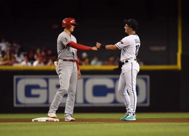 Shohei Ohtani of the Los Angeles Angels fist bumps with Josh Rojas of the Arizona Diamondbacks after hitting a double at Chase Field on June 11, 2021...