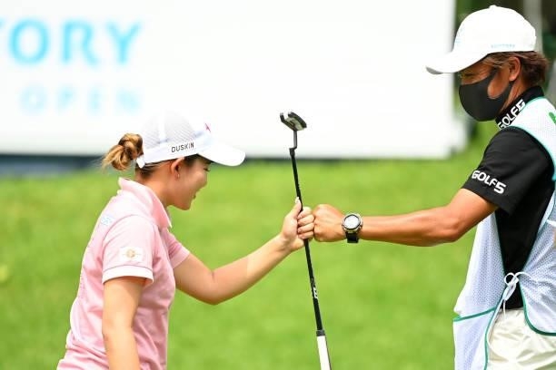 Hikaru Yoshimoto of Japan fist bumps with her caddie as she holes out with the birdie on the 18th green during the final round of the Ai Miyazato...