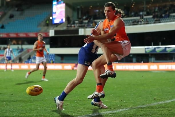 Isaac Cumming of the Giants handballs whilst being tackled during the round 13 AFL match between the North Melbourne Kangaroos and the Greater...