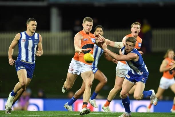 Jack Ziebell of the Kangaroos tries to block the kick by Jacob Hopper of the Giants during the round 13 AFL match between the North Melbourne...