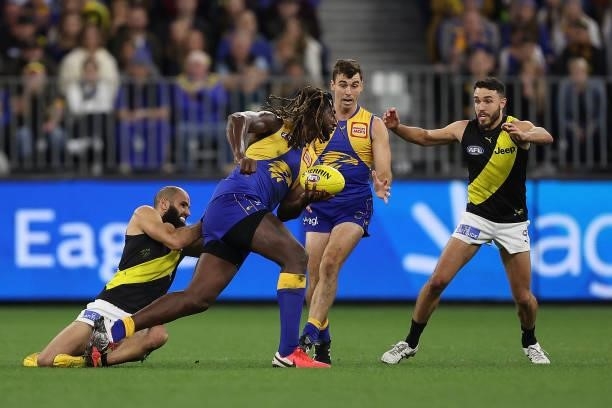 Nic Naitanui of the Eagles looks to handball against Bachar Houli of the Tigers during the round 14 AFL match between the West Coast Eagles and the...