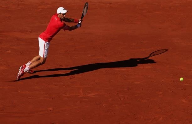 Novak Djokovic of Serbia stretches to play a backhand in his Men's Singles Final match against Stefanos Tsitsipas of Greece during Day Fifteen of the...