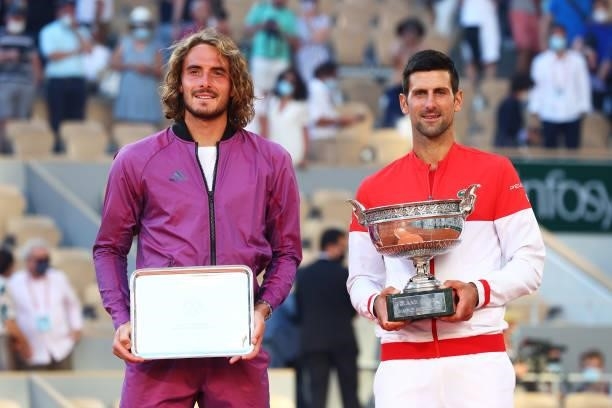 Runner-up Stefanos Tsitsipas of Greece and winner Novak Djokovic of Serbia pose with their respective trophies on the podium after the Men's Singles...
