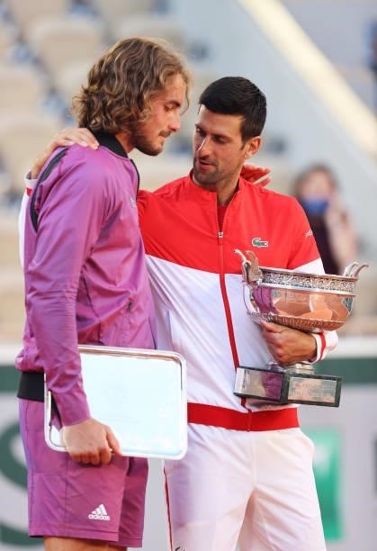 Runner-up Stefanos Tsitsipas of Greece is consoled by winner Novak Djokovic of Serbia as they hold their respective trophies on the podium after the...
