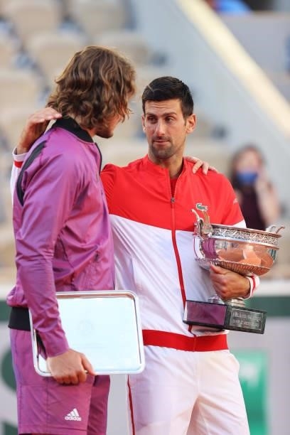 Runner-up Stefanos Tsitsipas of Greece is consoled by winner Novak Djokovic of Serbia as they hold their respective trophies on the podium after the...