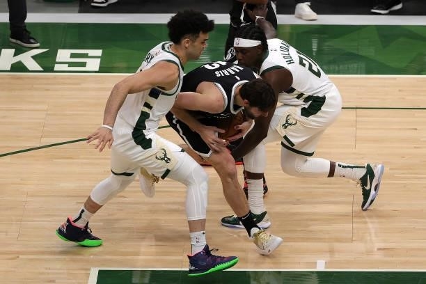 Joe Harris of the Brooklyn Nets is defended by Elijah Bryant and Jrue Holiday of the Milwaukee Bucks during the second half of Game Four of the...