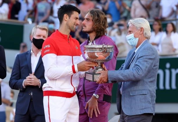 Winner Novak Djokovic of Serbia receives the trophy from Bjorn Borg while Jim Courier and finalist Stefanos Tsitsipas of Greece look on during the...