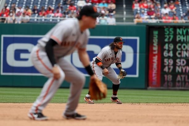 Wilmer Flores and Brandon Crawford of the San Francisco Giants follow the ball against the Washington Nationals at Nationals Park on June 13, 2021 in...