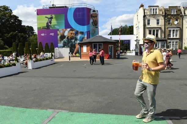 Spectator walks in the grounds carrying a drink and wearing a face mask during Day 1 of the cinch Championships at The Queen's Club on June 14, 2021...