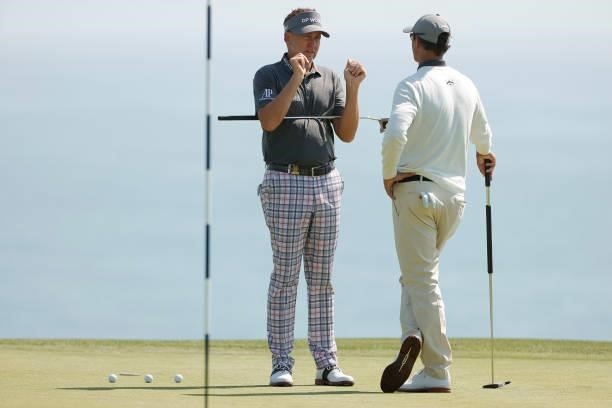 Ian Poulter of England and Adam Scott of Australia talk on the fourth green during a practice round prior to the start of the 2021 U.S. Open at...
