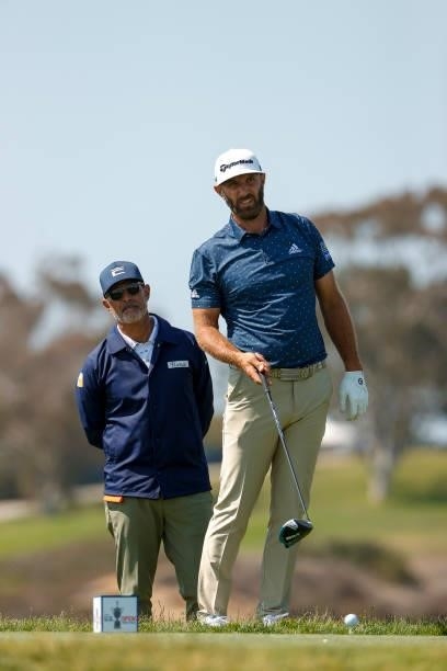 Dustin Johnson of the United States prepares to hit his tee shot on the fifth hole as coach Claude Harmon III looks on during a practice round prior...