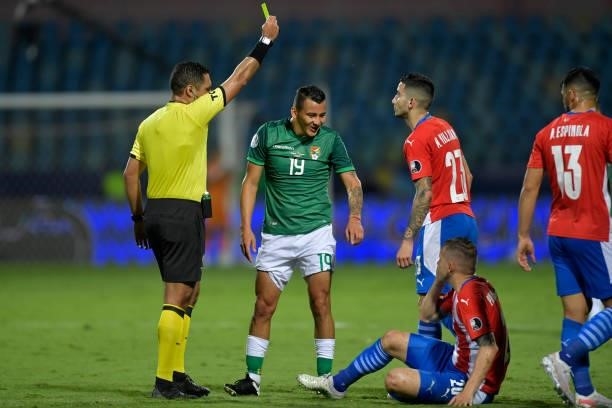 Referee Diego Mirko Haro shows a yellow card to Jorge Enrique Flores of Bolivia after a foul against Robert Piris da Motta of Paraguay during a Group...