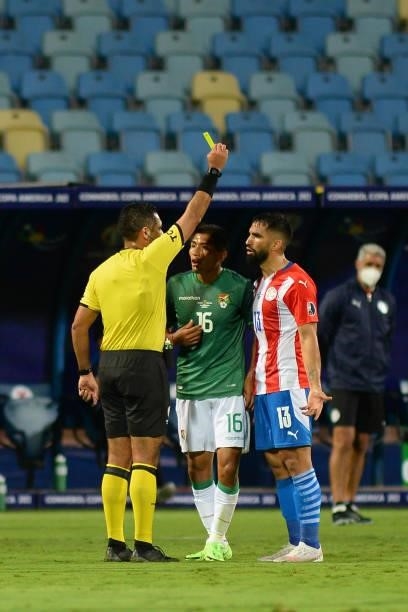 Referee Diego Mirko Haro shows a yellow card to Alberto Espinola of Paraguay during a Group A match between Paraguay and Bolivia at Estádio Olímpico...