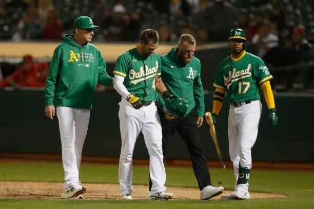 Chad Pinder of the Oakland Athletics is assisted from the field after being hit by a pitch from Junior Guerra of the Los Angeles Angels in the bottom...