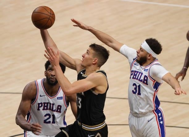 Bogdan Bogdanovic of the Atlanta Hawks drives against Joel Embiid and Seth Curry of the Philadelphia 76ers during the second half of game 4 of the...