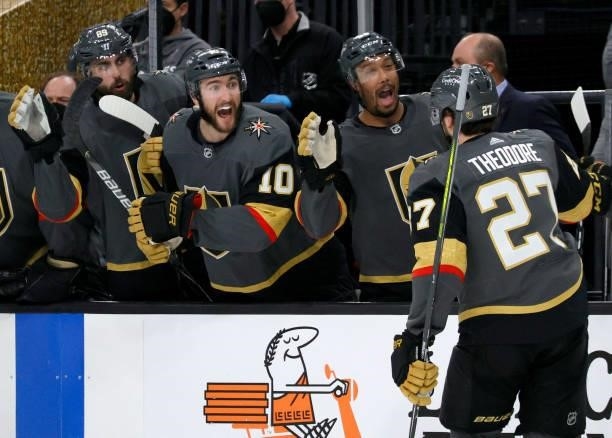 Shea Theodore of the Vegas Golden Knights celebrates with teammates Alex Tuch, Nicolas Roy and Keegan Kolesar on the bench after Theodore assisted...