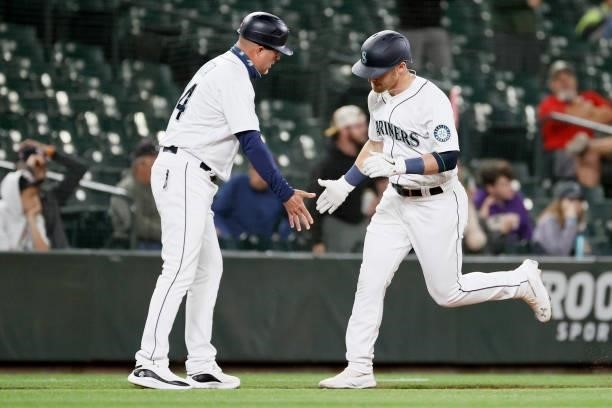 Third base coach Manny Acta and Jake Bauers of the Seattle Mariners react after a home run by Bauers during the eighth inning against the Minnesota...