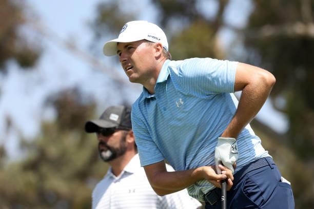 Jordan Spieth of the United States and caddie Michael Greller watch Spieth's tee shot on the 18th hole during a practice round prior to the start of...