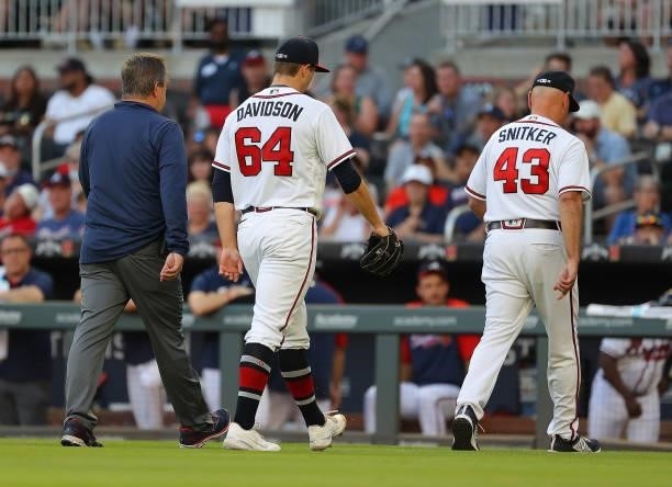 Tucker Davidson of the Atlanta Braves walks off the field behind Brian Snitker after an injury in the third inning against the Boston Red Sox at...