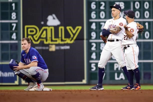 Brock Holt of the Texas Rangers waits for a call at second ahead of Carlos Correa of the Houston Astros and Jose Altuve during the fifth inning at...