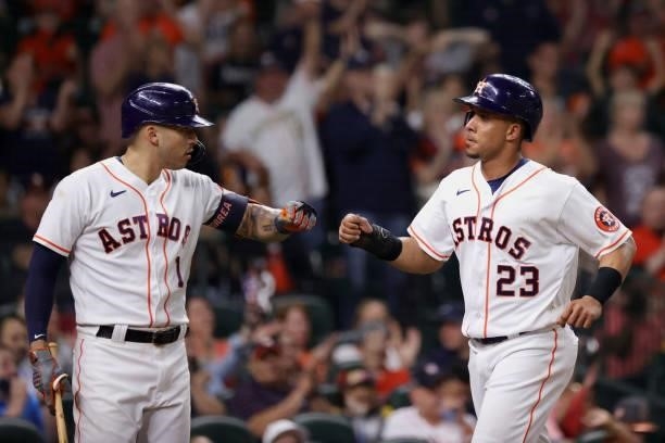 Michael Brantley of the Houston Astros fist bumps Carlos Correa after scoring during the sixth inning against the Texas Rangers at Minute Maid Park...