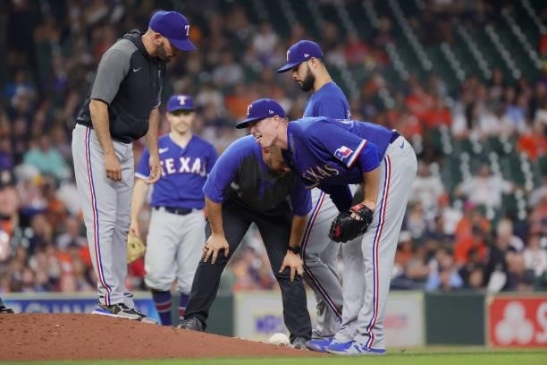 The Texas Rangers training staff comes to check on Kyle Gibson of the Texas Rangers after being hit by a ball from Michael Brantley of the Houston...