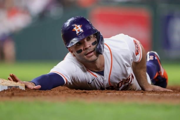Jose Altuve of the Houston Astros slides back to first base during the sixth inning against the Texas Rangers at Minute Maid Park on June 15, 2021 in...