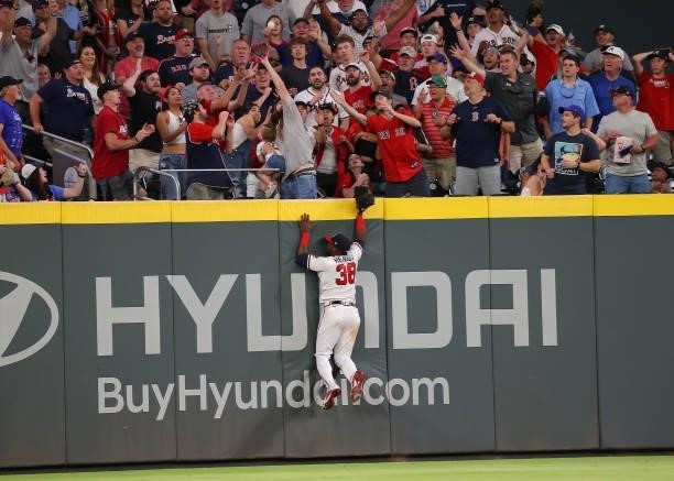 Guillermo Heredia of the Atlanta Braves leaps into the outfield wall as a three-run homer hit by Alex Verdugo of the Boston Red Sox flies over the...