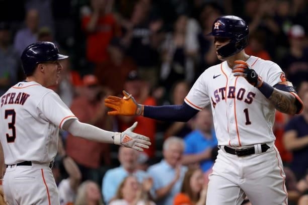 Carlos Correa of the Houston Astros high fives Myles Straw after hitting a solo home run during the ninth inning to force extra innings against the...