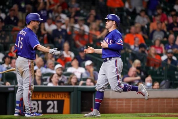 Nick Solak of the Texas Rangers high fives Brock Holt after Holt scored during the tenth inning against the Houston Astros at Minute Maid Park on...