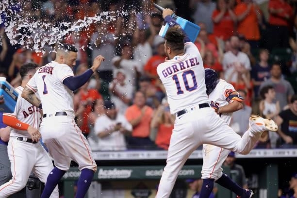 Yuli Gurriel throws gatorade on Jose Altuve of the Houston Astros after hitting a grand slam to defeat the Texas Rangers during the tenth inning by a...
