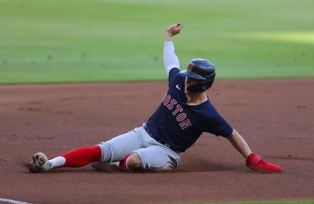 Enrique Hernandez of the Boston Red Sox slides safely into third base on a sacrifice fly in the first inning against the Atlanta Braves at Truist...