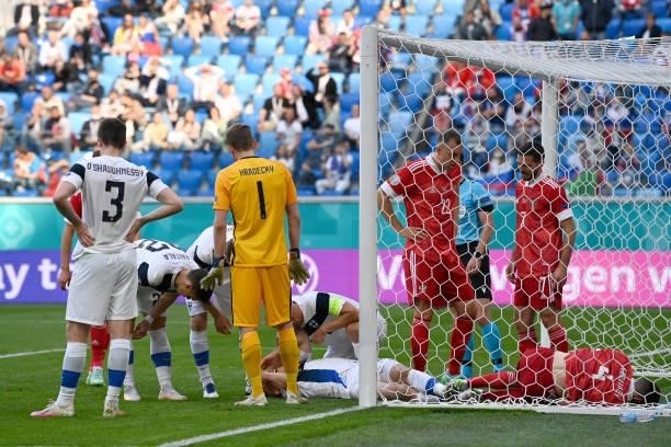 Vyacheslav Karavaev of Russia and Jere Uronen of Finland react as they lie injured after colliding with the goal post during the UEFA Euro 2020...