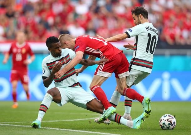 Andras Schaefer of Hungary is challenged by Nelson Semedo and Bernardo Silva of Portugal during the UEFA Euro 2020 Championship Group F match between...