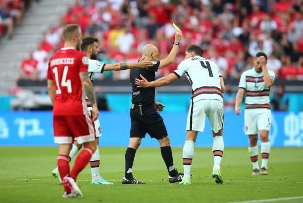 Referee, Cueneyt Cakir shows the yellow card to Ruben Dias of Portugal during the UEFA Euro 2020 Championship Group F match between Hungary and...