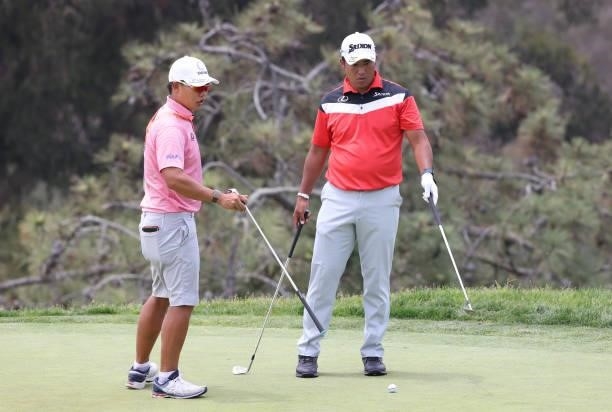 Hideki Matsuyama of Japan and caddie Shota Hayafuji stand on the 13th green during a practice round prior to the start of the 2021 U.S. Open at...