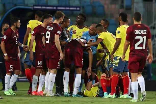 Referee Eber Aquino attempts to help a player of Colombia who suffered an injury as Davinson Sanchez of Colombia argues with players of Venezuela...