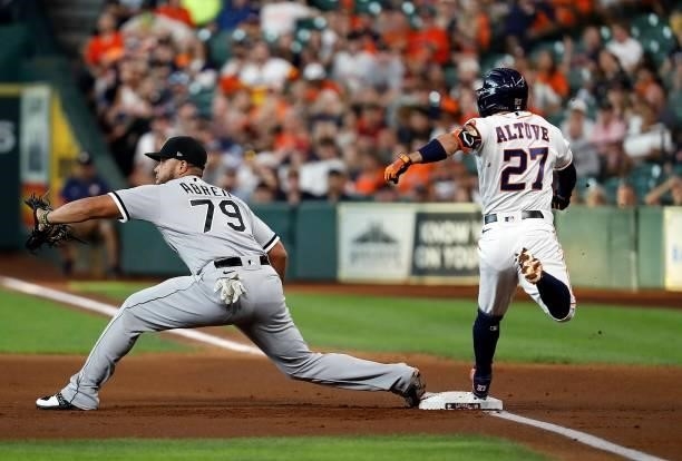 Jose Altuve of the Houston Astros beats the throw to first base as Jose Abreu of the Chicago White Sox stretches for the ball in the first inning at...