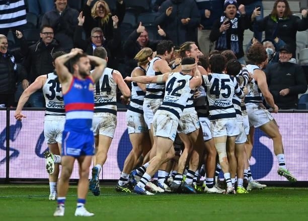 Gary Rohan of the Cats is congratulated by team mates after kicking a goal to win the match as Caleb Daniel of the Bulldogs looks dejected during the...
