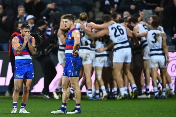 Gary Rohan of the Cats is congratulated by team mates after kicking a goal to win the match as Caleb Daniel and Taylor Duryea of the Bulldogs look...
