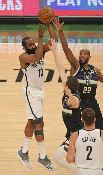 James Harden of the Brooklyn Nets passes over Khris Middleton and Pat Connaughton of the Milwaukee Bucks at Fiserv Forum on June 17, 2021 in...