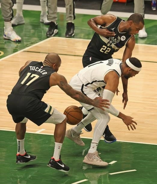 Bruce Brown of the Brooklyn Nets looses control of the ball under pressure from P.J. Tucker and Khris Middleton of the Milwaukee Bucks at Fiserv...