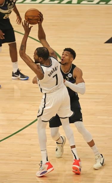 Kevin Durant of the Brooklyn Nets passes under pressure from Giannis Antetokounmpo of the Milwaukee Bucks at Fiserv Forum on June 17, 2021 in...