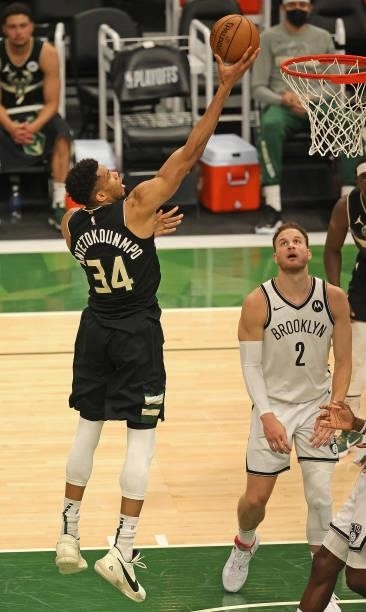Giannis Antetokounmpo of the Milwaukee Bucks lays in a shot over Blake Griffin of the Brooklyn Nets at Fiserv Forum on June 17, 2021 in Milwaukee,...